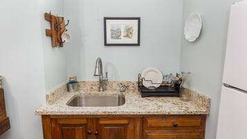 A kitchen with a granite countertop, wooden cabinets, a stainless steel sink, and a hanging light fixture.