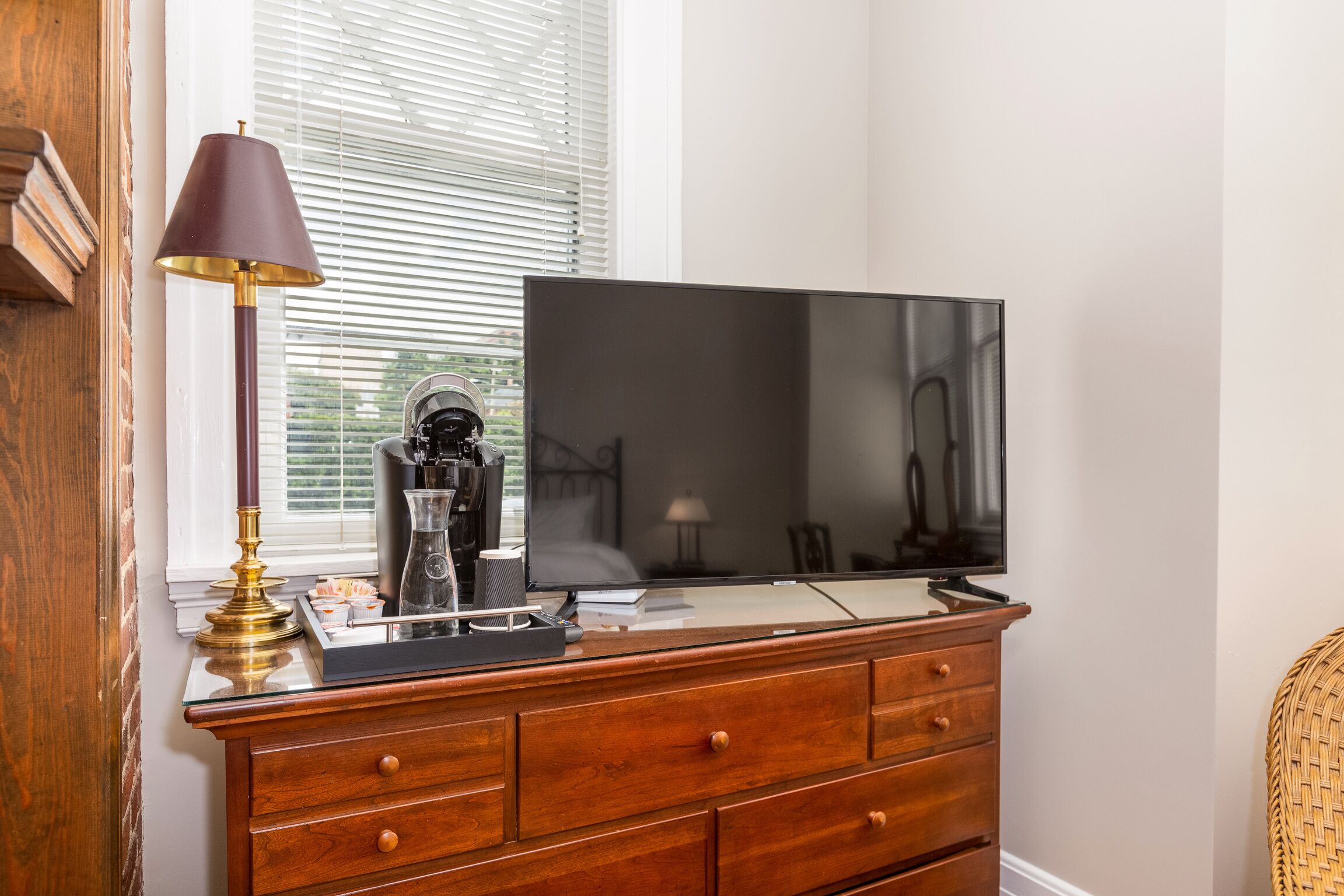 A wooden dresser with a flat-screen TV, a brass lamp, and a decorative item on top.