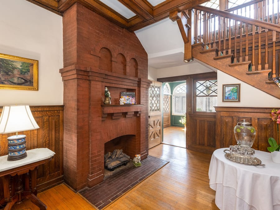 Quarto com lareira de tijolos, escada de madeira e uma mesa com abajur.