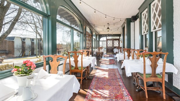 A long dining area with tables set for service, large windows, and a view of the outside. - The Shaffner Inn (Winston-Salem)