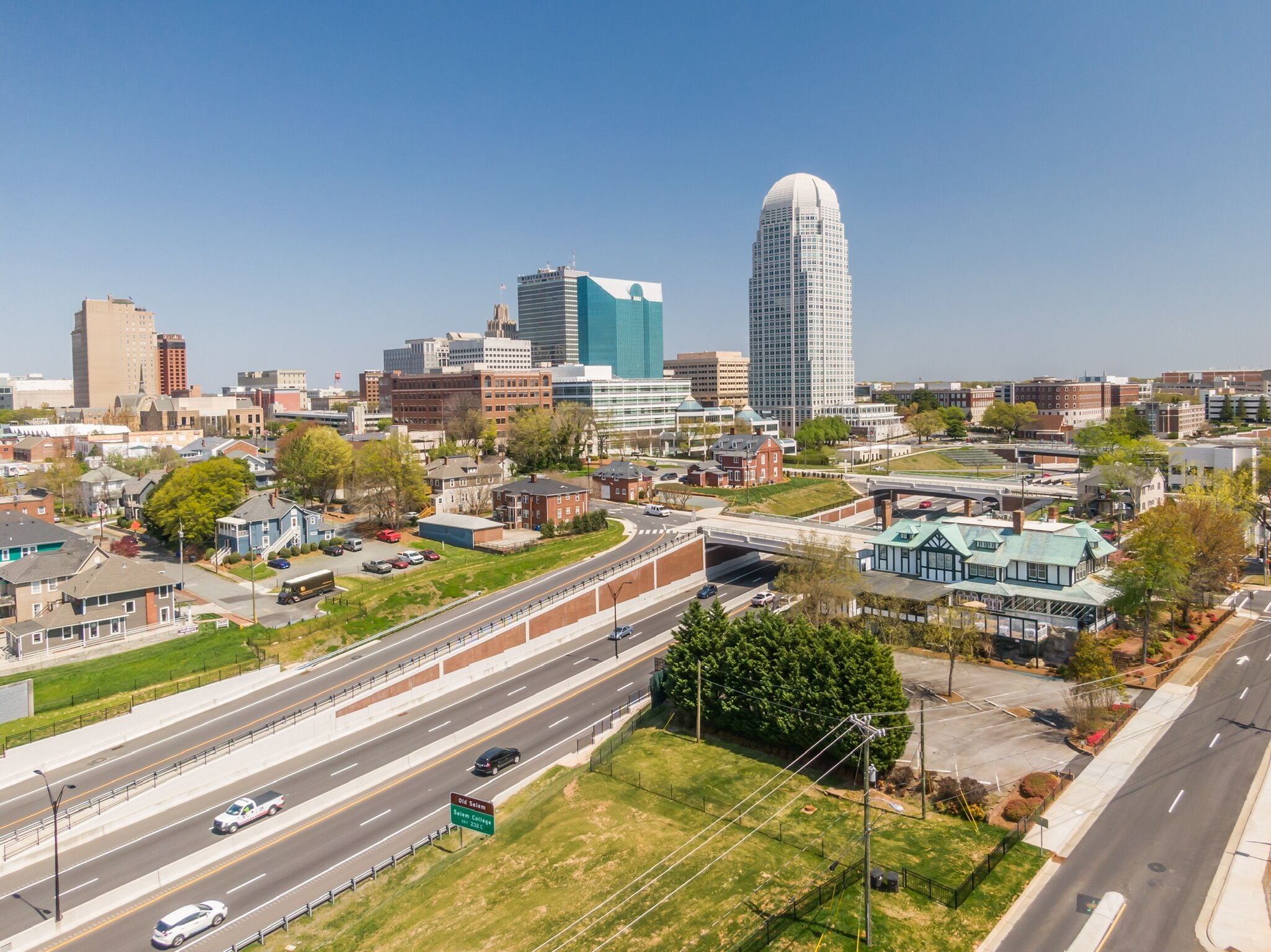 A cityscape with a prominent curved skyscraper, a highway, and surrounding residential and commercial buildings.