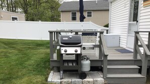 Un barbecue sur une terrasse en bois, avec des marches menant à une maison.