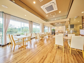 A spacious hotel dining area with wooden flooring, white chairs, and large windows offering a view of greenery. - Nonsmoking Japanesestyle room 125 tatami mats / Minamimatsuura-gun Nagasaki (Minamimatsuura-gun)