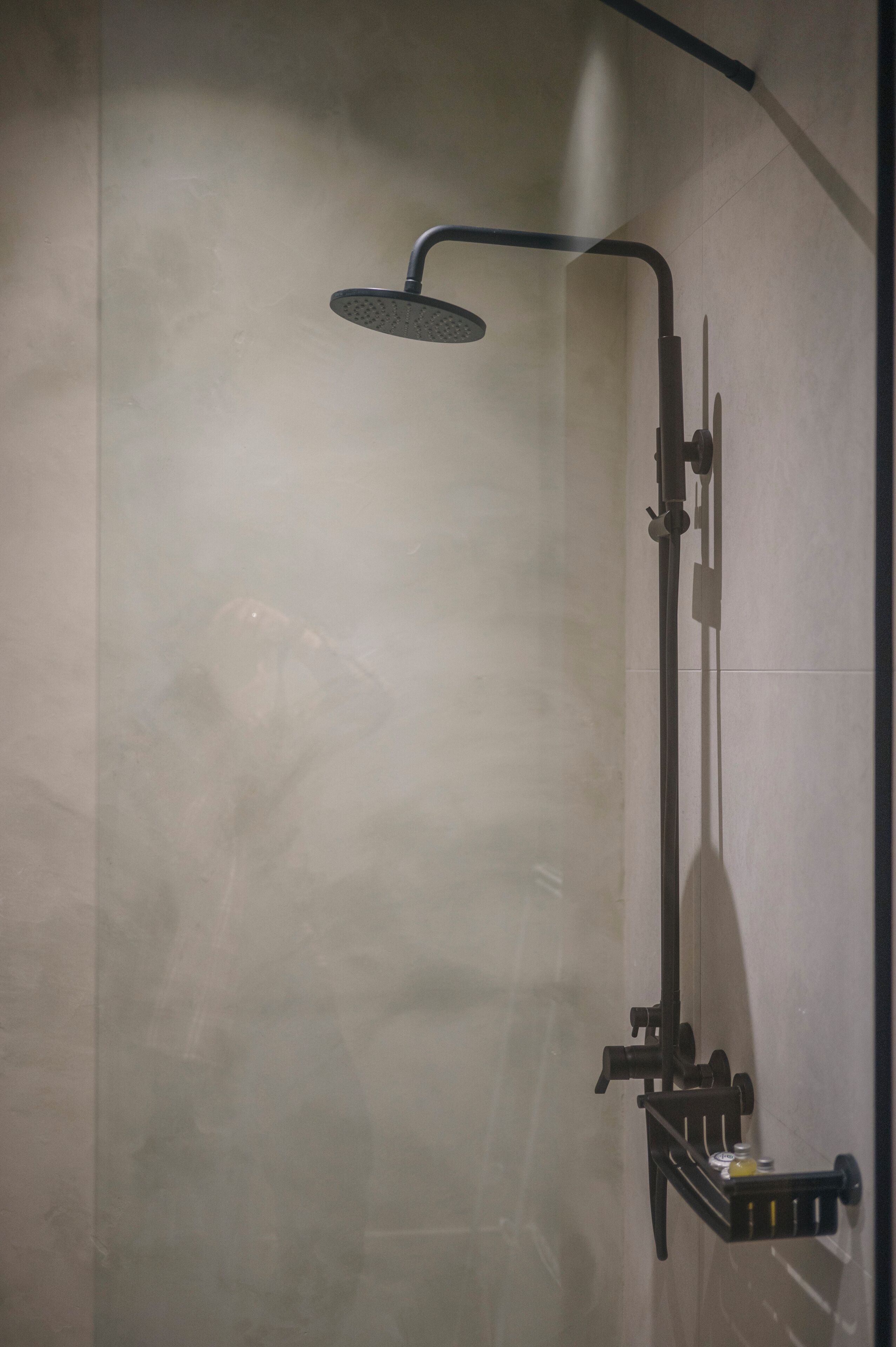 A modern shower with a handheld showerhead and a wall-mounted control panel.