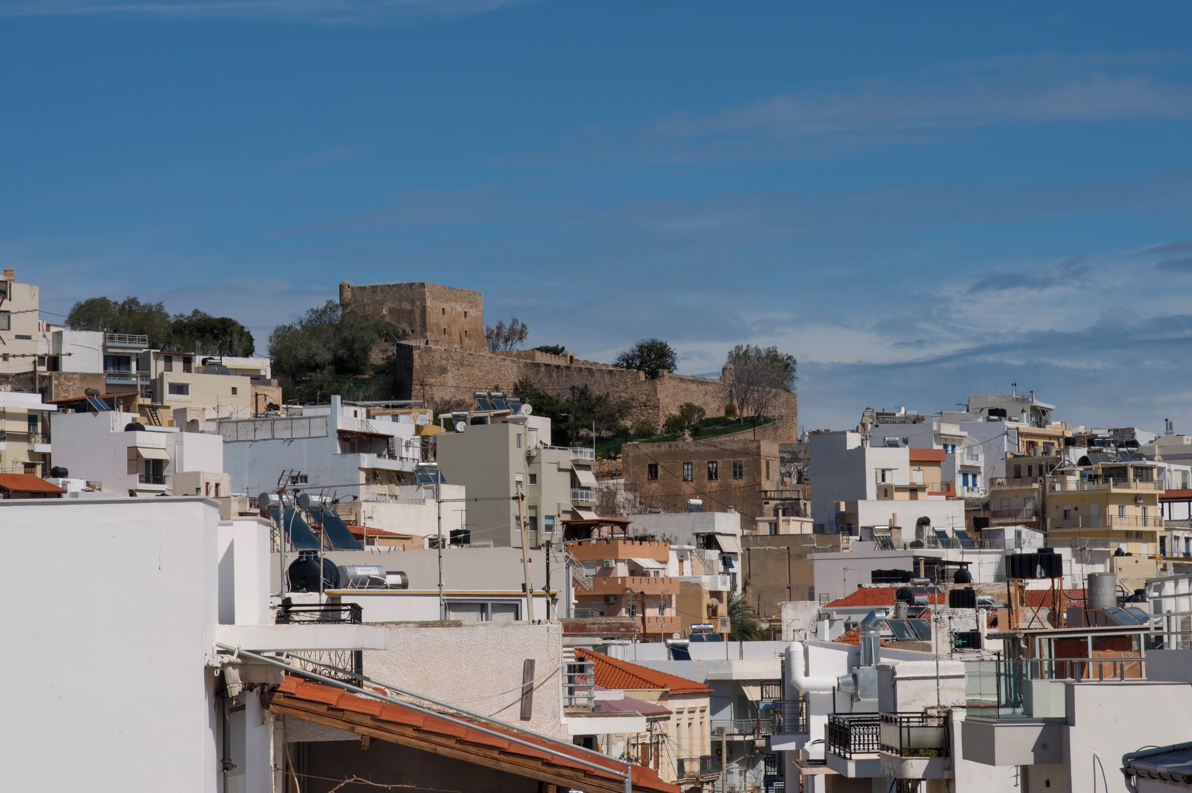 A densely packed urban area with a prominent historical building on a hill, surrounded by modern residential buildings.