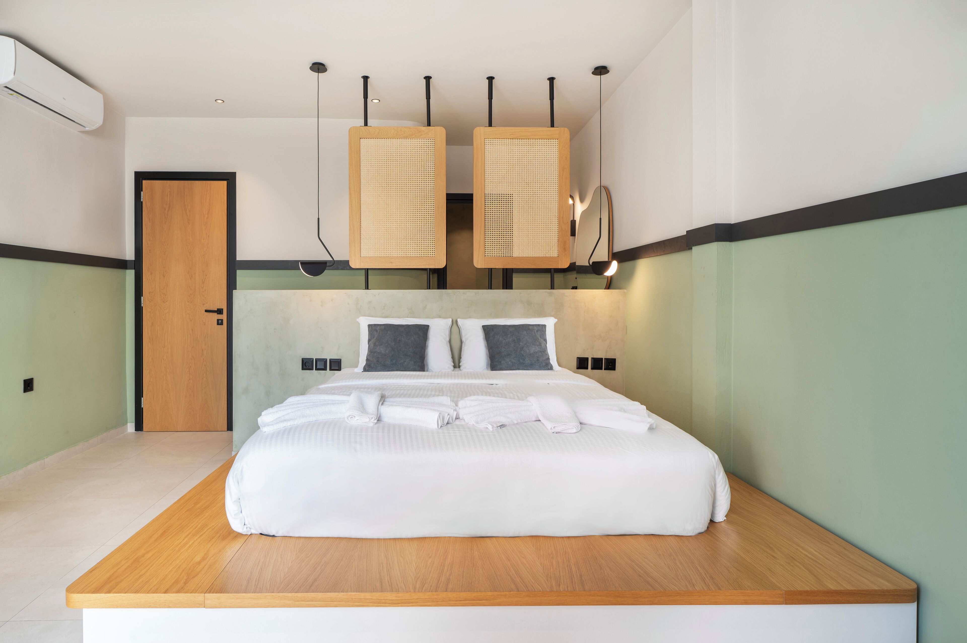 A modern hotel room with a large bed, wooden headboard, and two wall-mounted air purifiers.