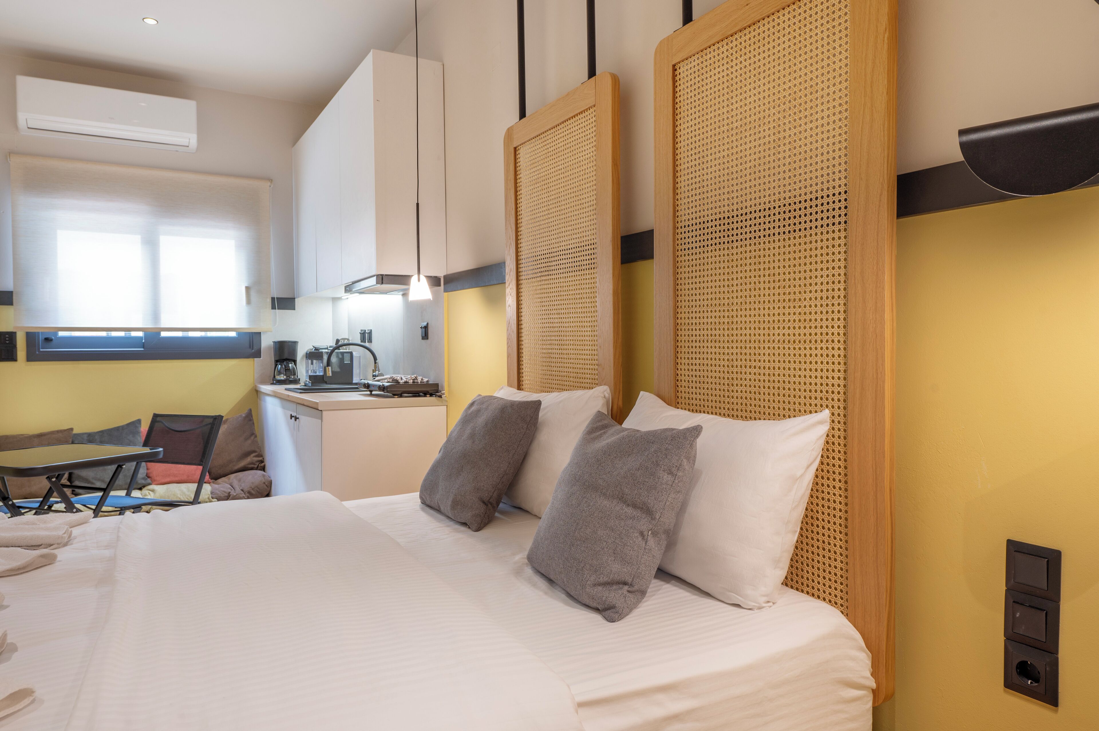 A hotel room with a large bed, a small kitchenette, and a dining area.