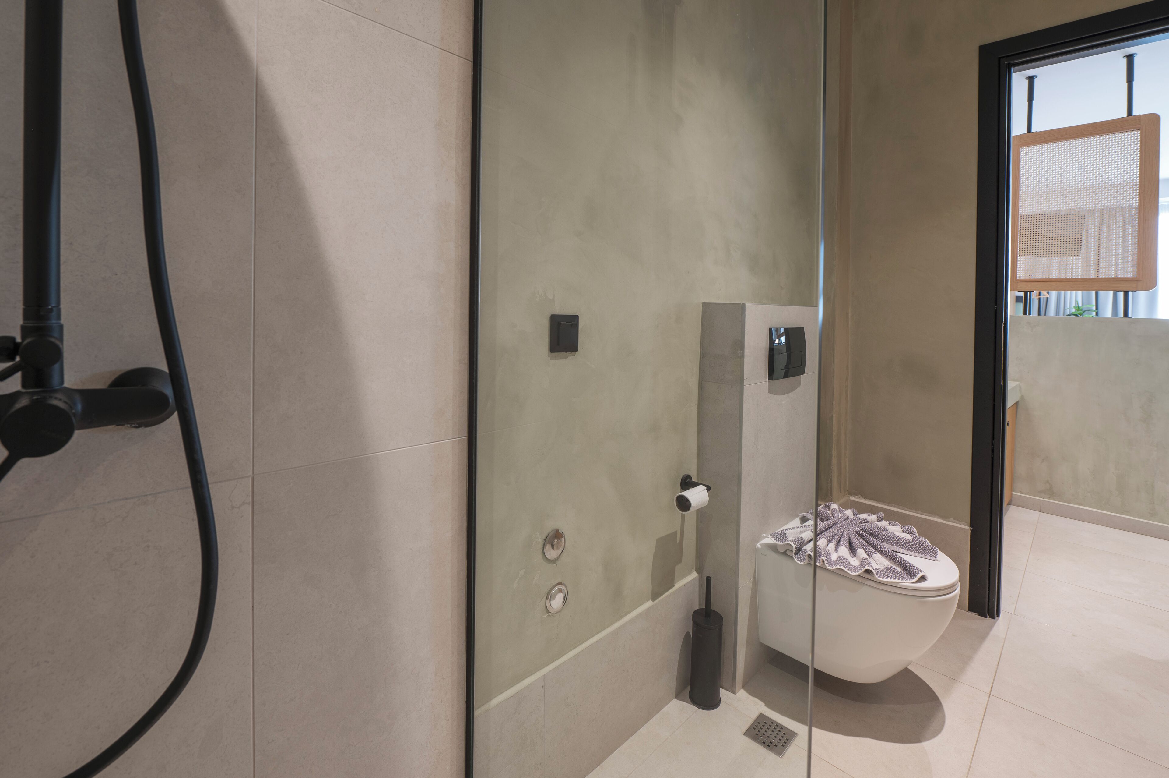 Un baño moderno con cabina de ducha de vidrio, un inodoro con toalla y un cabezal de ducha visible.