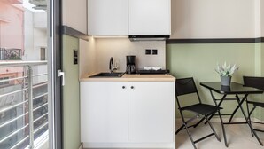 A compact kitchen with white cabinets, a black coffee maker, and a small table with two chairs. - Casa di Cornaro (Sitia)