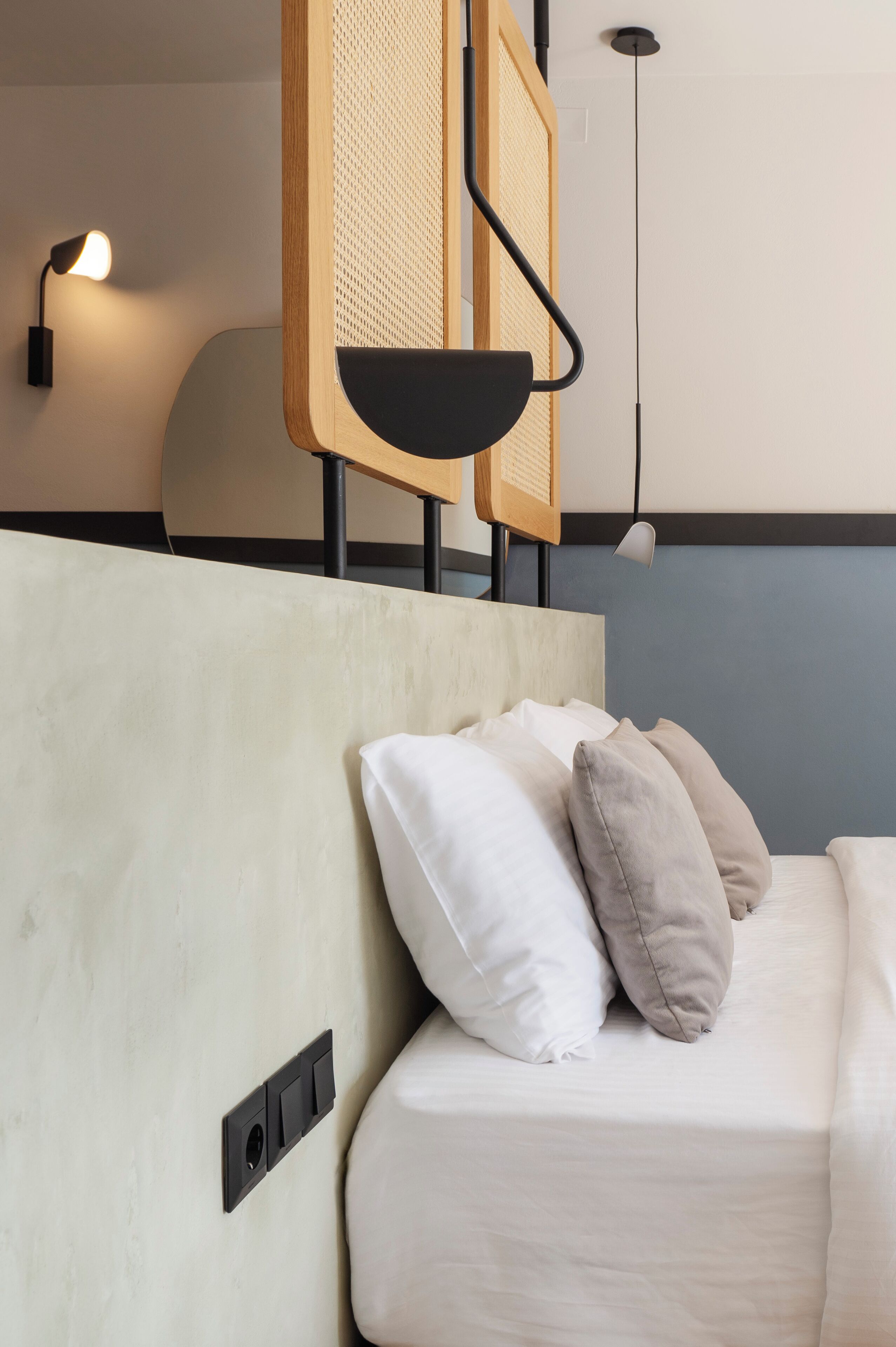 Een moderne hotelkamer met een bed, een hoofdeinde, een wandlamp en een plafondlamp.