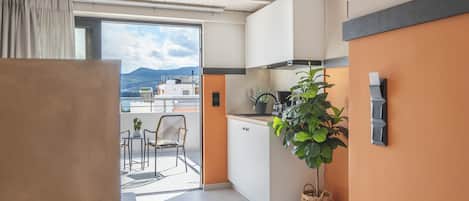 Una cocina moderna con gabinetes blancos, un ventanal y vistas a edificios y montañas.