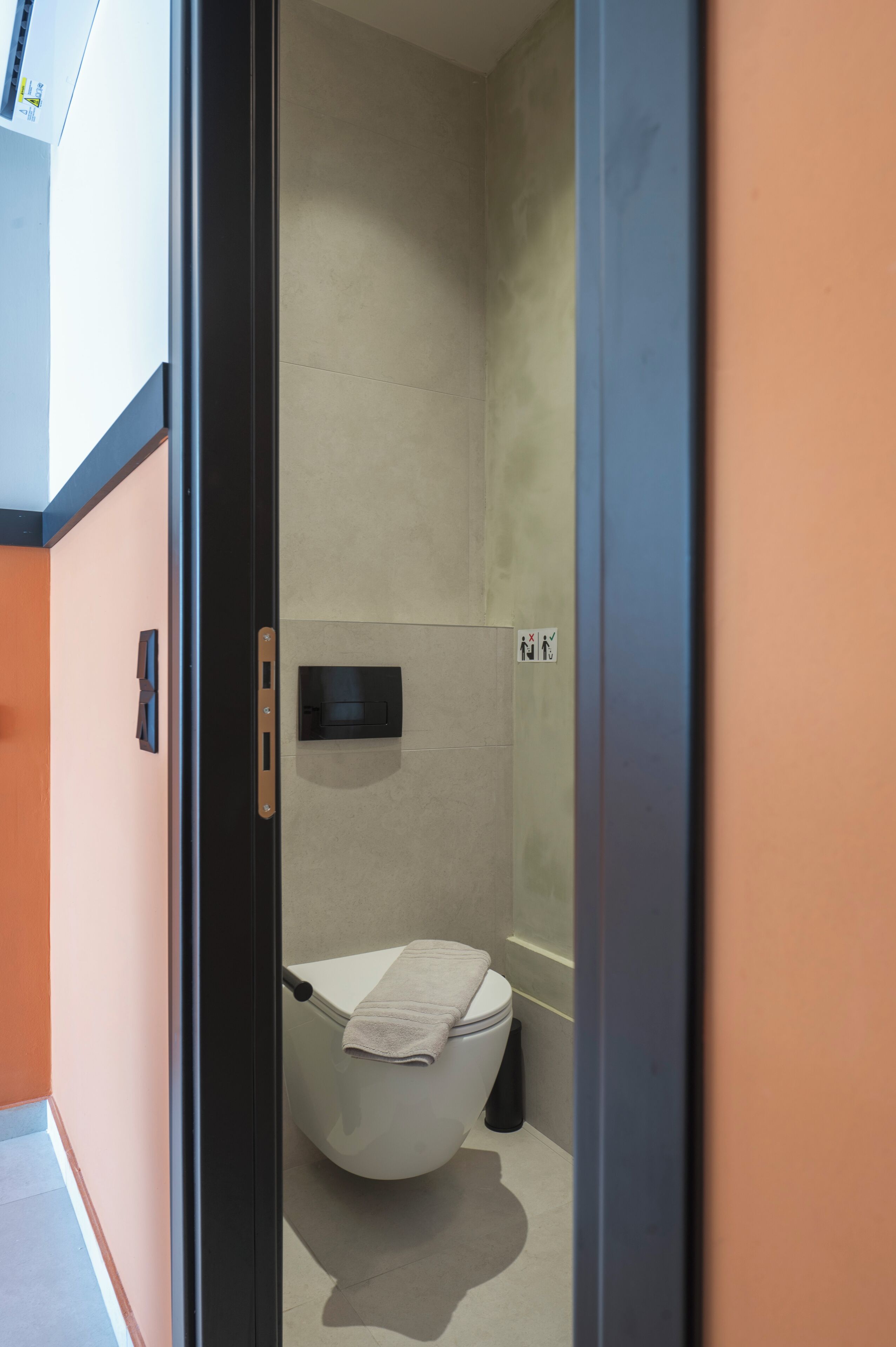 A modern bathroom with a toilet, towel, and a trash bin.