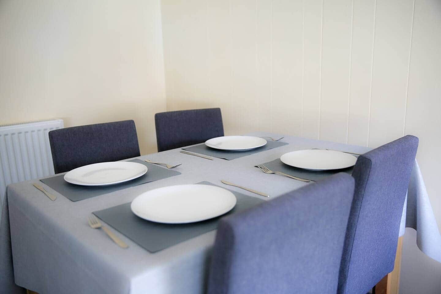 Een eettafel gedekt met borden, bestek en servetten.