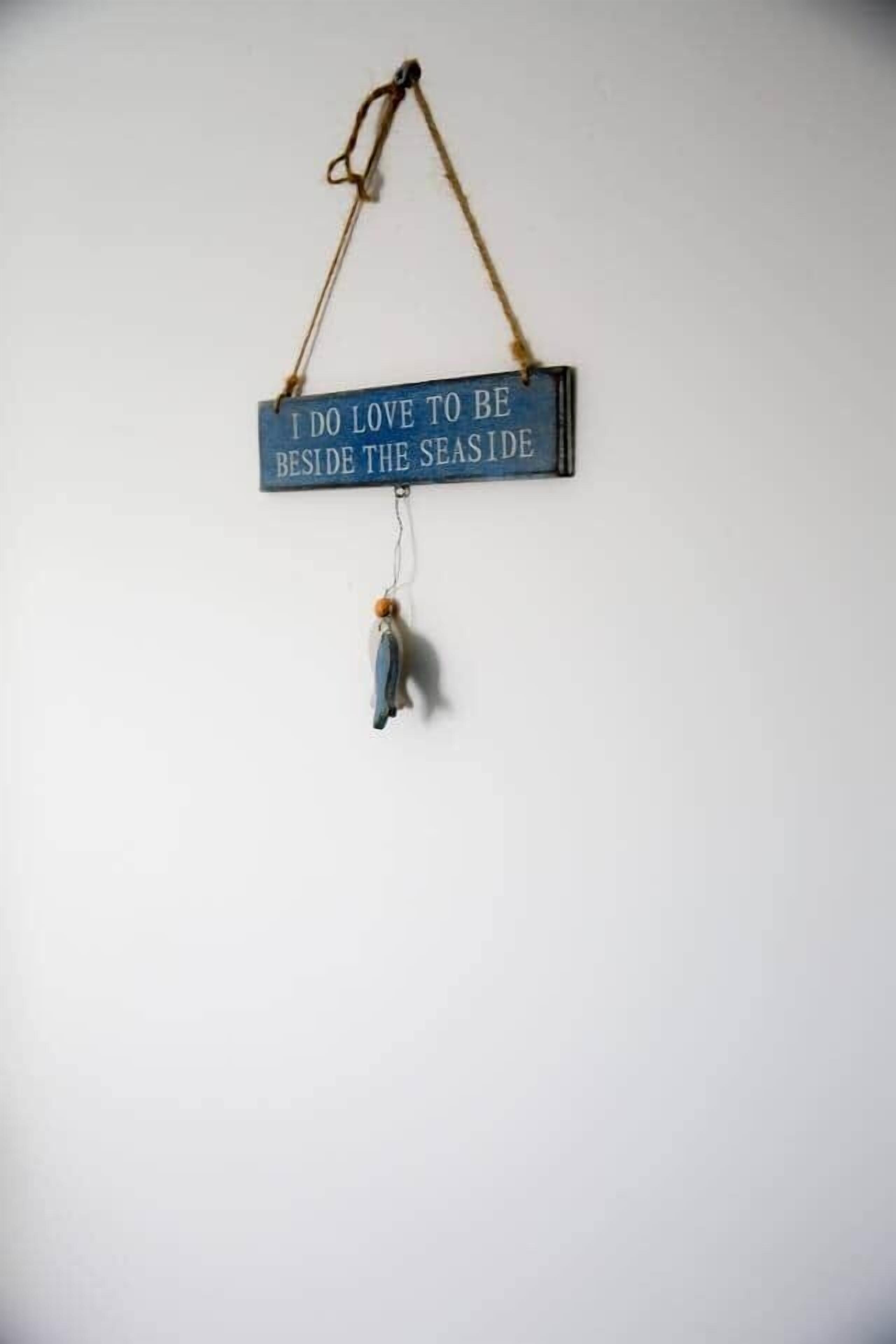Ein Schild mit dem Text „Ich liebe es, am Meer zu sein“ an einer Wand.
