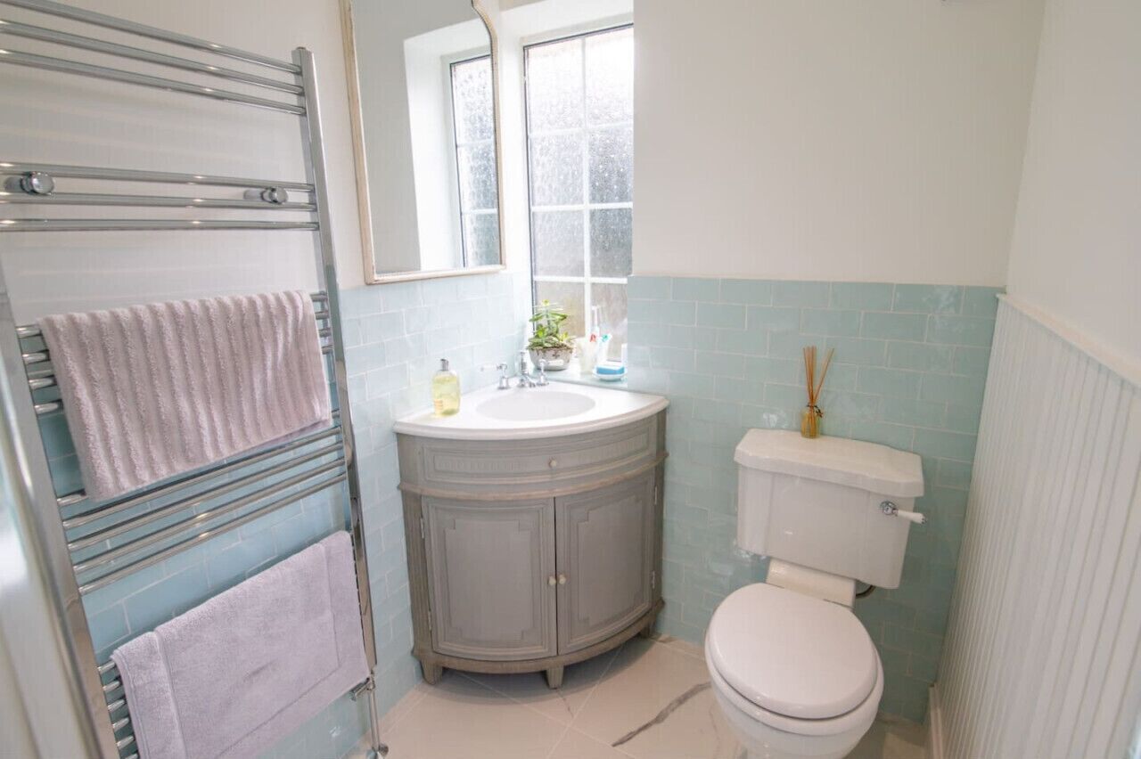 Ein Badezimmer mit Toilette, Waschbecken mit Spiegel darüber und Handtuchhalter mit zwei Handtüchern.