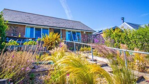 Een huis met een bakstenen gevel, een schuin dak en een veranda met blauwe luiken.