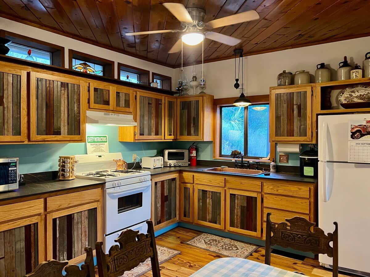 A kitchen with wooden cabinets, a stove, a microwave, and a refrigerator.