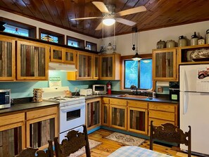 A kitchen with wooden cabinets, a stove, a microwave, and a refrigerator. - Top of the Stairs Old Bisbee|Park & Walk to Main Street (Bisbee)