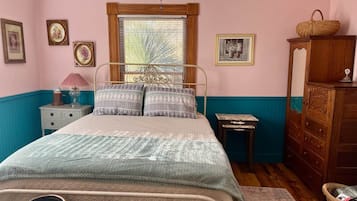 A bedroom with a bed, a nightstand, a dresser, and a window with blinds.