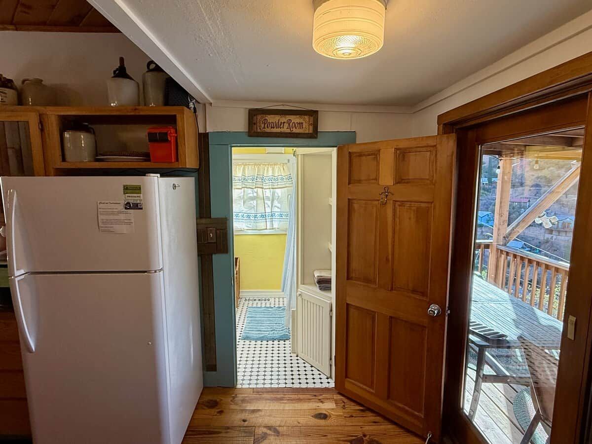 A kitchen with a refrigerator, wooden cabinets, and a sign reading 'Powder Room'.