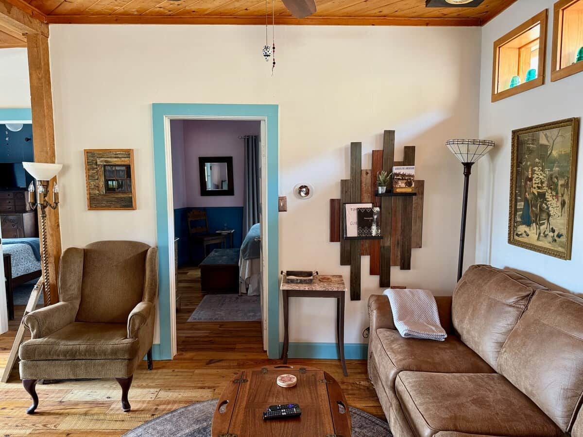 A cozy living room with a brown leather sofa, a wooden coffee table, and a blue-framed doorway leading to another room.