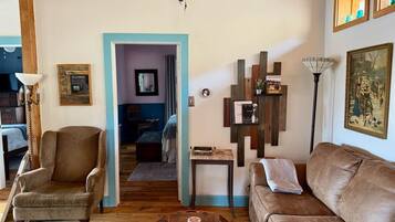 A cozy living room with a brown leather sofa, a wooden coffee table, and a blue-framed doorway leading to another room.