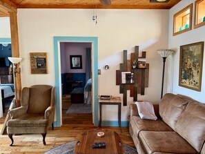 A cozy living room with a brown leather sofa, a wooden coffee table, and a blue-framed doorway leading to another room. - Top of the Stairs Old Bisbee|Park & Walk to Main Street (Bisbee)