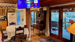 A room with a wooden ceiling, a dining area with a table and chairs, a TV displaying a Roku interface, and a view of a deck through a glass door. - 3-bedroom cabin in Old Bisbee (Bisbee)