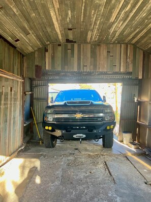 A black pickup truck parked inside a wooden structure with a metal roof, possibly a garage or shed. - Top of the Stairs Old Bisbee|Park & Walk to Main Street (Bisbee)