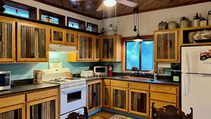 A kitchen with wooden cabinets, a stove, a microwave, and a refrigerator. - 3-bedroom cabin in Old Bisbee (Bisbee)