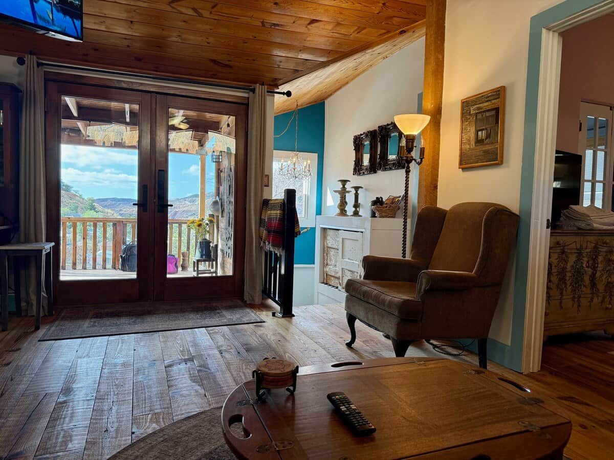 A cozy living room with a wooden floor, a brown leather armchair, a coffee table, and a fireplace.