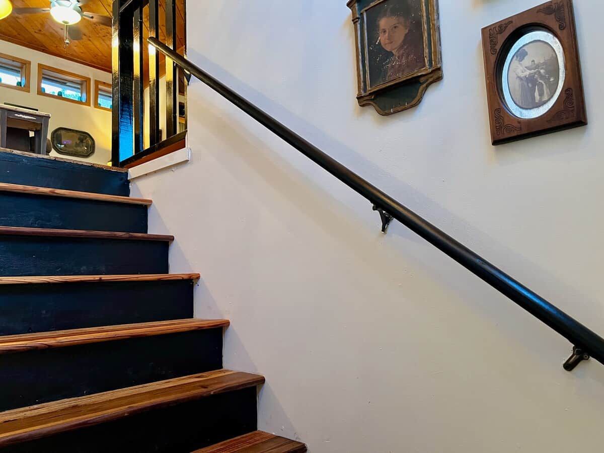 A staircase with wooden steps and a black handrail.