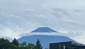 A mountain with a cloud base, surrounded by trees and buildings.