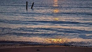 A sunset over a calm sea with a sandy beach and two vertical poles in the water. - Luxurious Victorian Home by the sea - Myana House (Lowestoft)