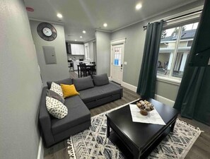 Un salon moderne avec un canapé gris, une table basse noire et un tapis à motifs.