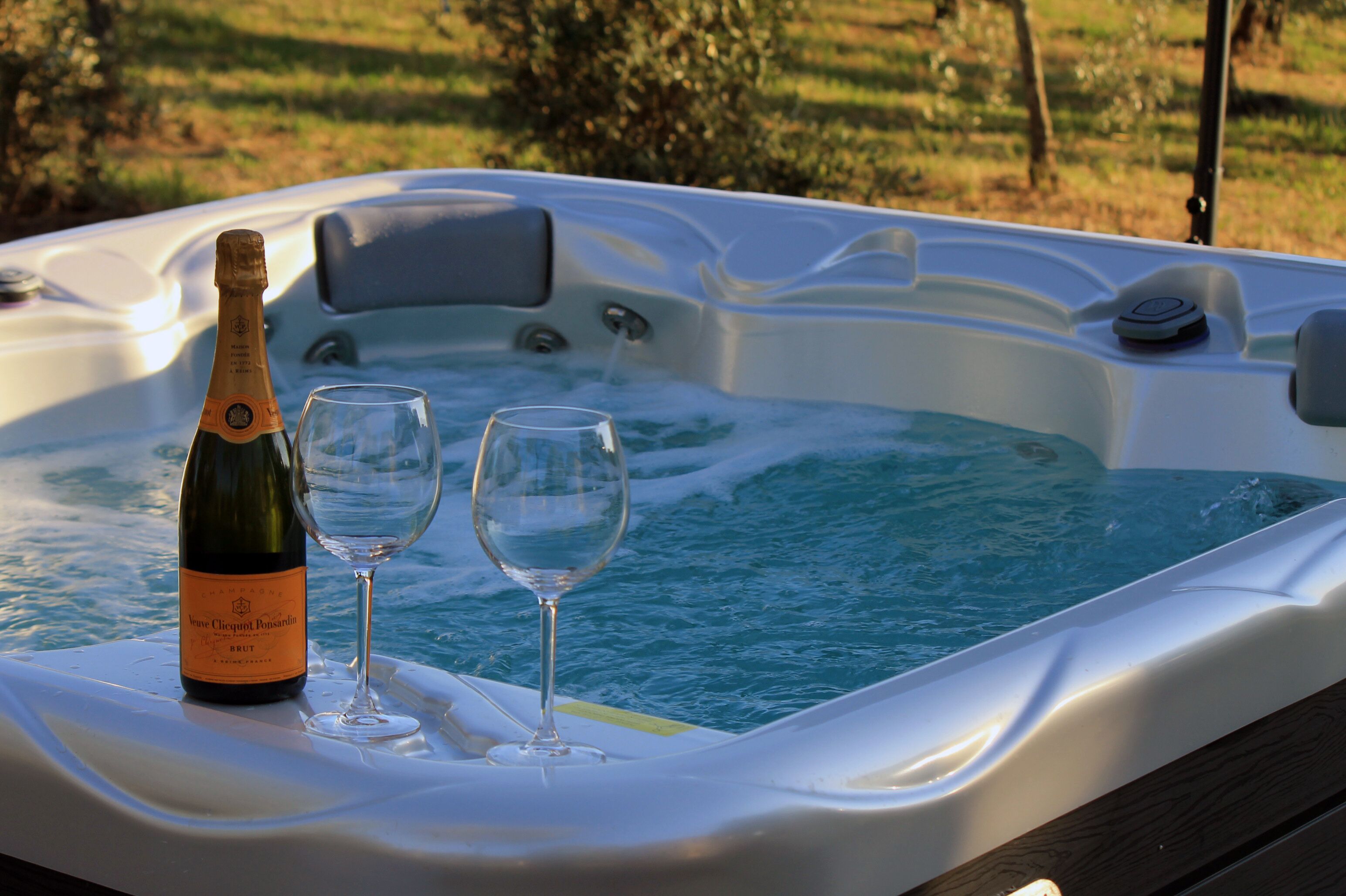 Un bain à remous avec une bouteille de champagne et deux verres sur une table.