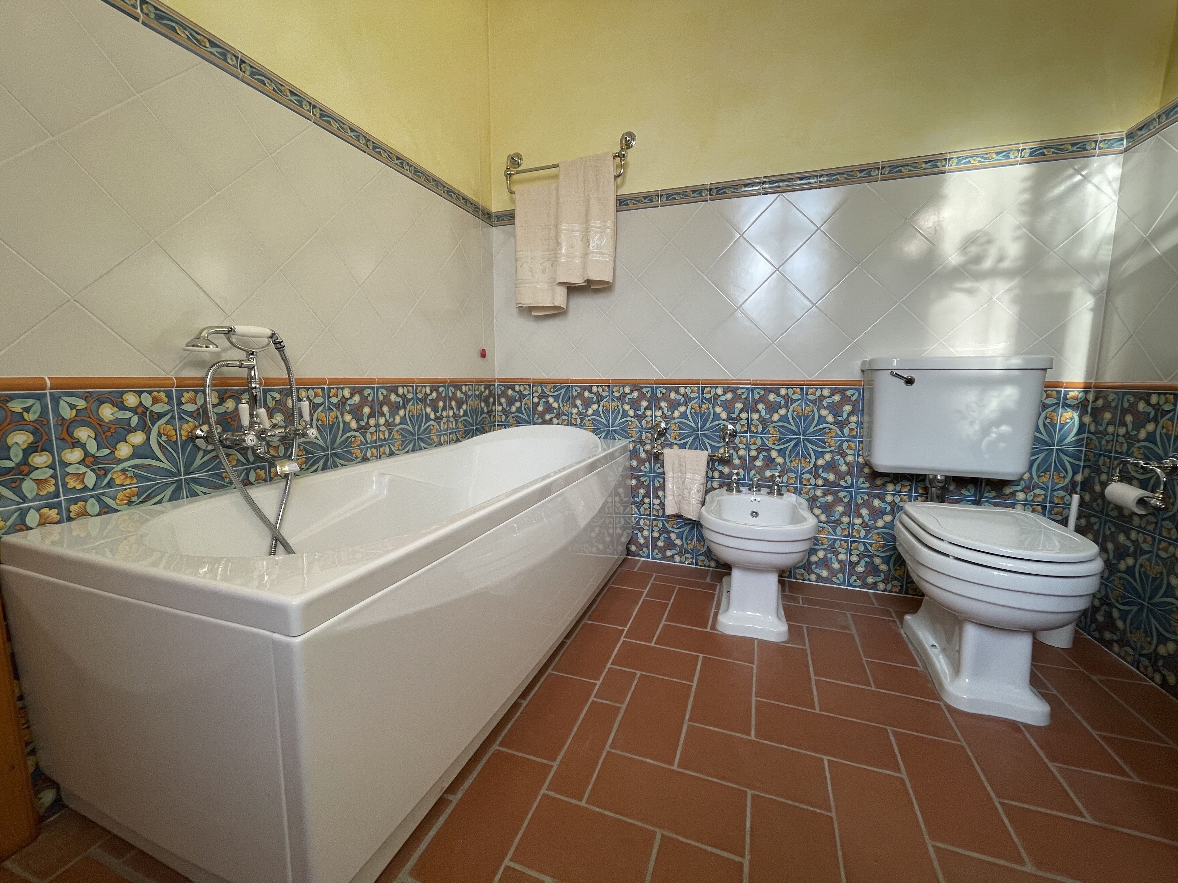 Een badkamer met een bad, toilet en bidet.