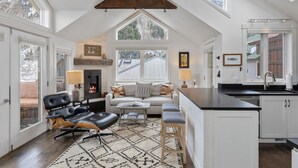 Ein geräumiges Loft mit hoher Decke, einer gemütlichen Sitzecke mit Kamin und einer Küche mit weißen Schränken.