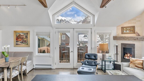 Ein gemütliches Wohnzimmer mit Kamin, einem Essbereich mit Tisch und Stühlen sowie einem großen Fenster mit Blick auf die Berge.