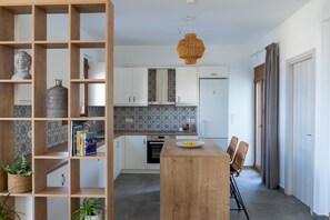Et moderne køkken med lyse skabe, en central ø og en hængende lampe.