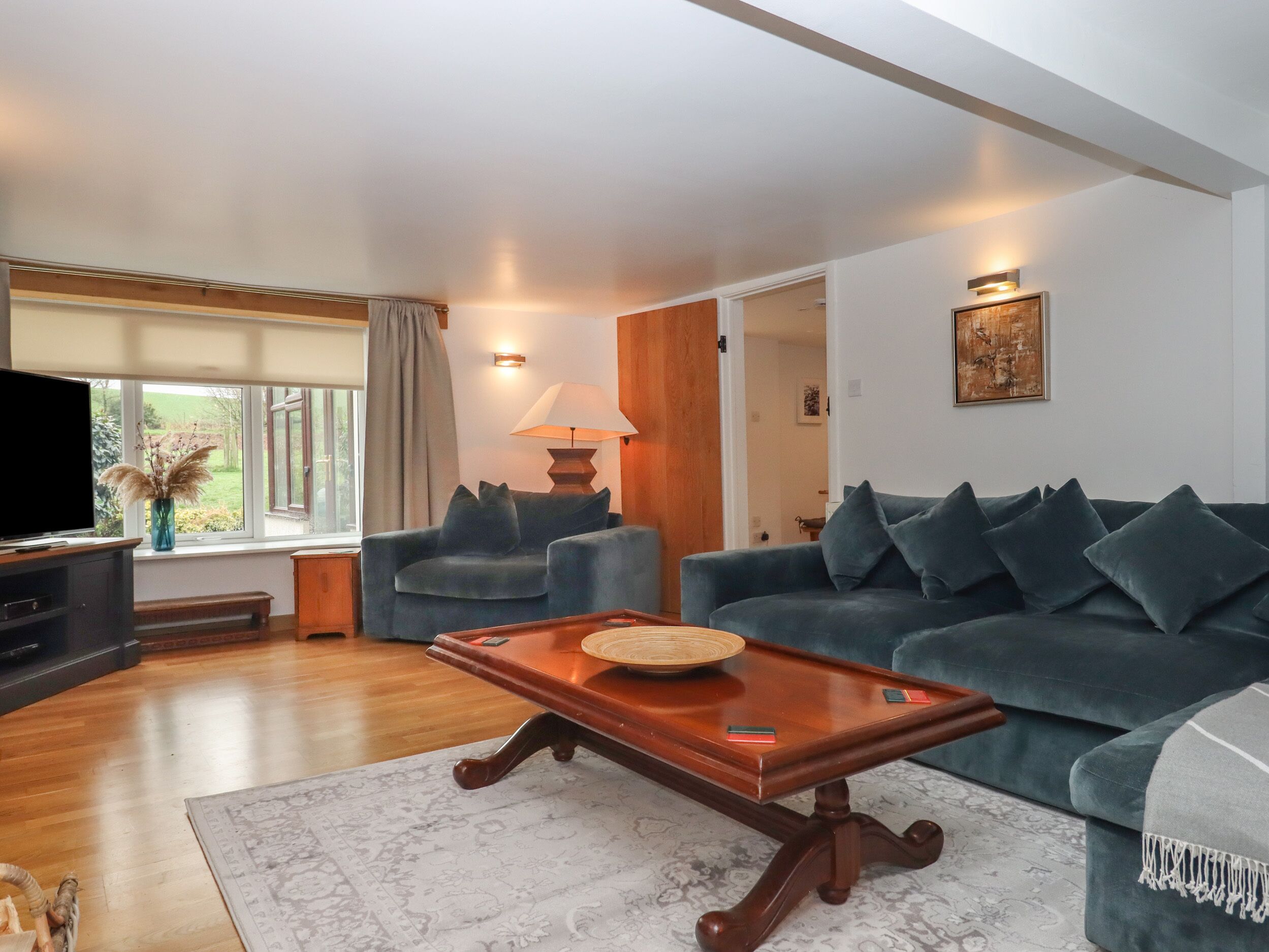 A living room with a dark blue sofa, a wooden coffee table, a TV, and a lamp.