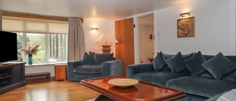 A living room with a dark blue sofa, a wooden coffee table, a TV, and a lamp.