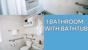Une salle de bain équipée d’une baignoire, de toilettes, d’un lavabo et de barres d’appui.