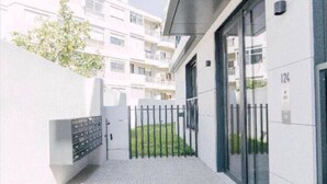 Een modern gebouw met een hekpoort, een klein stukje gazon en een parkeergarage op de achtergrond.