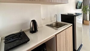 A modern kitchen with wooden cabinets, a stainless steel sink, a kettle, and a microwave.