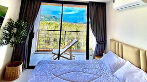 A bedroom with a large bed, a view of the outdoors, and an air conditioning unit.
