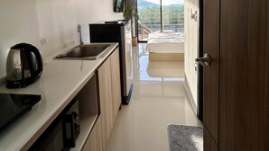 A modern kitchen with wooden cabinets, a built-in oven, and a sink. There is a view of a balcony with a mountain landscape.