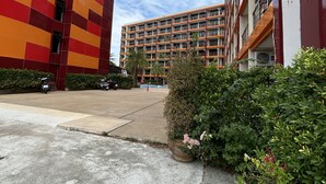 A multi-story building with a colorful facade and a parking area in front.