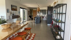 A modern kitchen with a central island, bar stools, and a dining area with a patterned rug. - Beachfront family home for 14 people (Zonza)