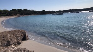 A beach with clear water, boats, and a rocky outcrop. - Beachfront family home for 14 people (Zonza)